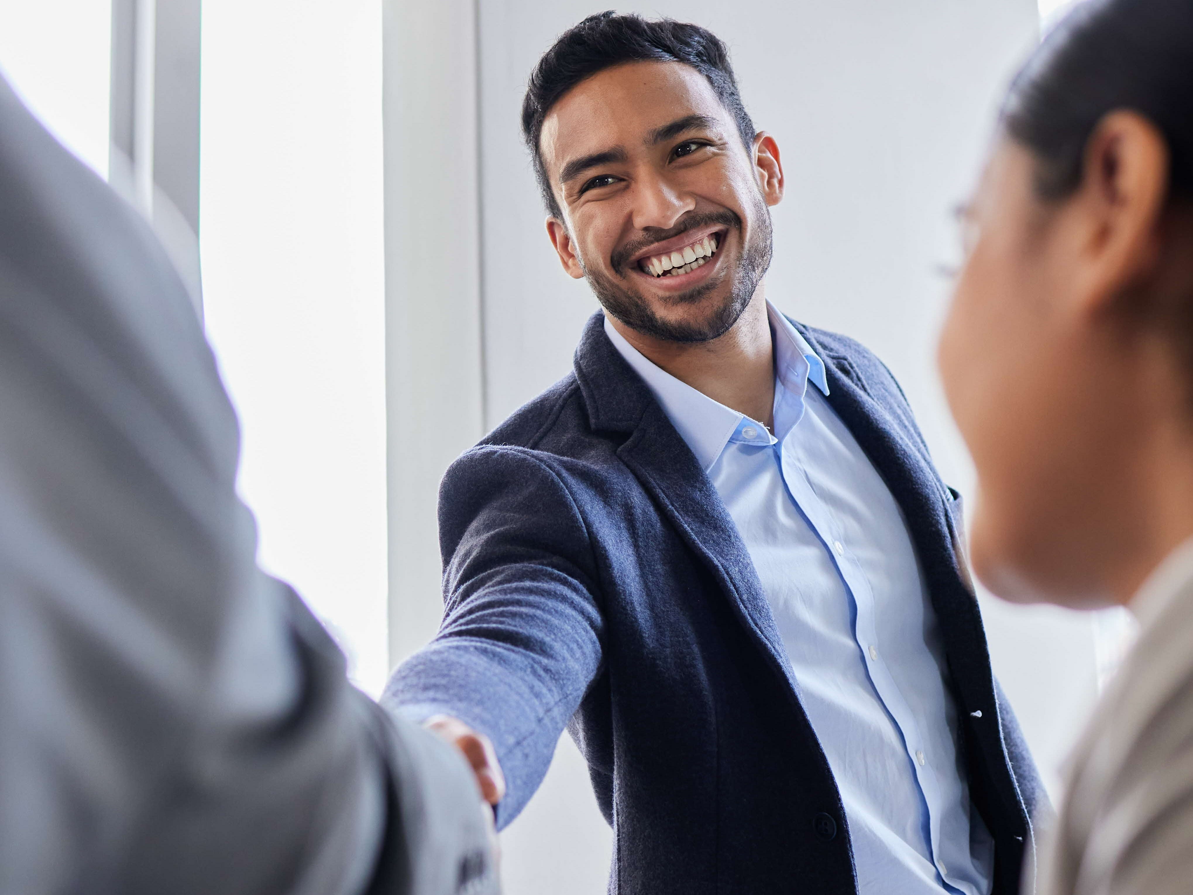 A man smiling and shaking hands with another man.
